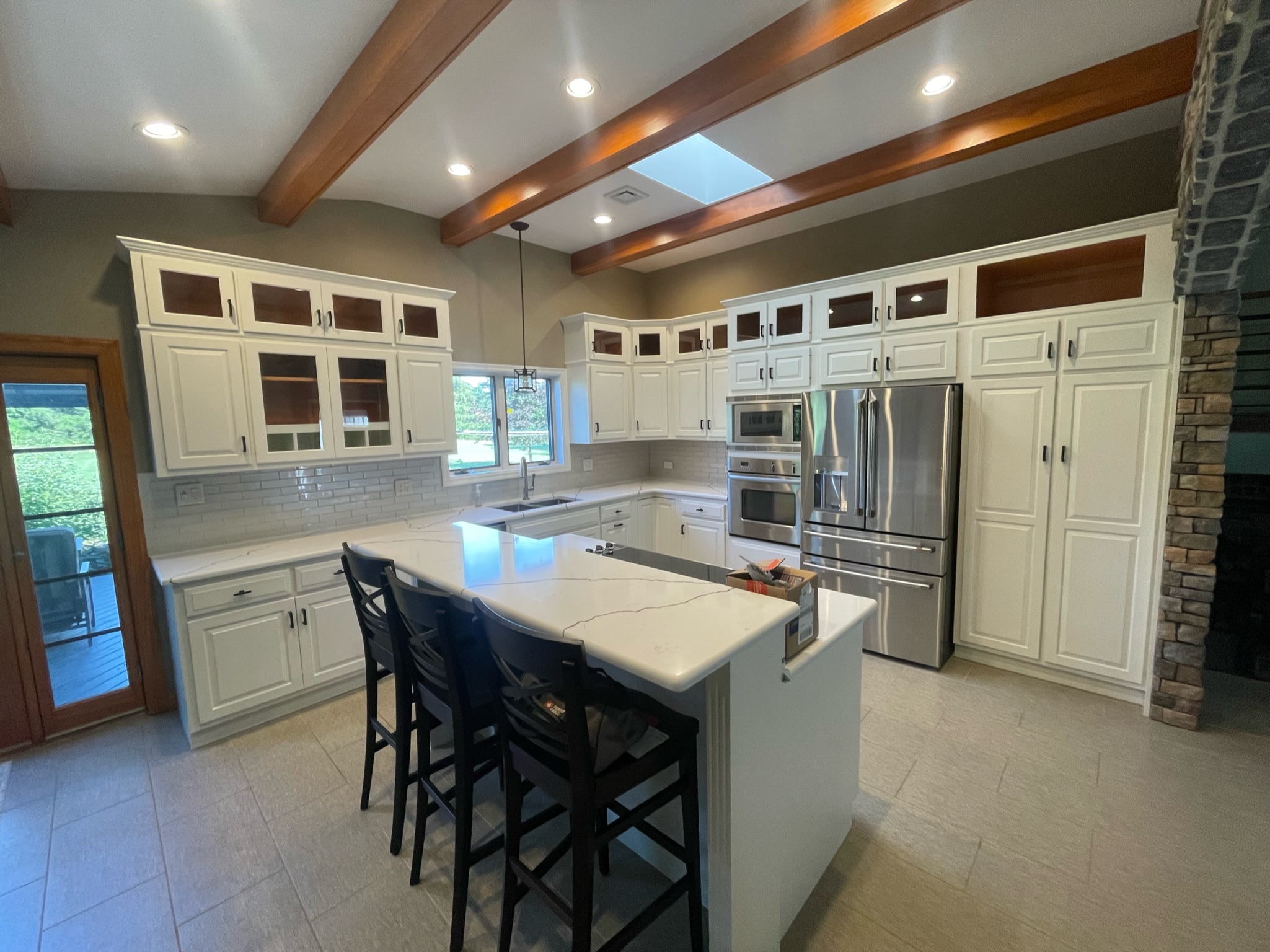 modern kitchen with refinished cabinets, updated hardware, white cabinetry, and open layout with island